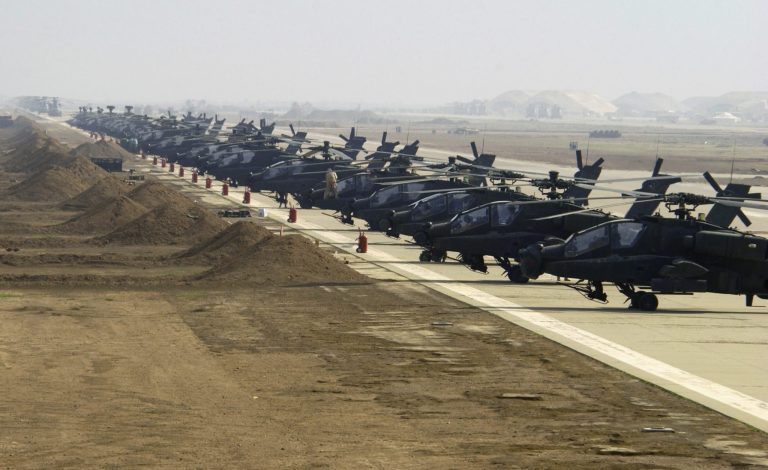 US Army (USA) AH-64D Apache Longbow helicopters line the ramp at an airfield in Iraq during Operation IRAQI FREEDOM.