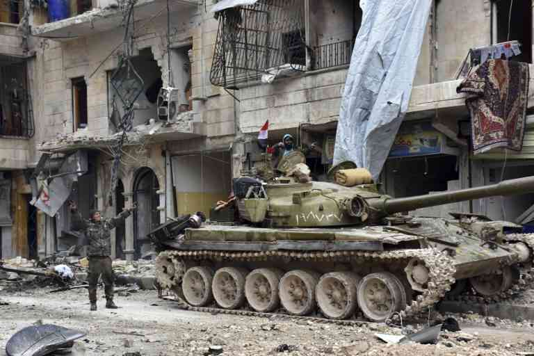 This photo released by the Syrian official news agency SANA, shows Syrian army soldiers flash the victory sign near their tank in the Sukkari neighborhood, east Aleppo, Syria, Friday, Dec 23, 2016. Syrian rebels outside Aleppo on Friday shelled a neighborhood in the northern city, killing three people in the first bombardment since government forces took control of the whole city after opposition fighters in the eastern parts withdrew, state TV reported. (SANA via AP)