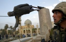 солдат США на фоне поверченного памятника Саддаму Хусейну