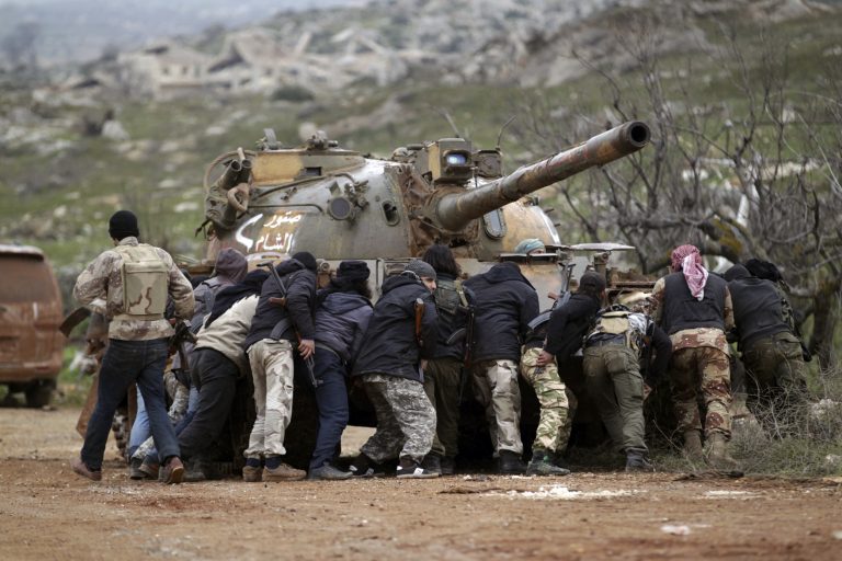 Fighters from the Suqour al-Sham Brigade, which is part of the Free Syrian Army, take cover from snipers behind a tank during what activists said were clashes with forces of Syria's President Bashar al-Assad, in the al-Arbaeen mountain area of western Idlib January 30, 2015. REUTERS/Khalil Ashawi  (SYRIA - Tags: POLITICS CIVIL UNREST CONFLICT TPX IMAGES OF THE DAY) - RTR4NNRX