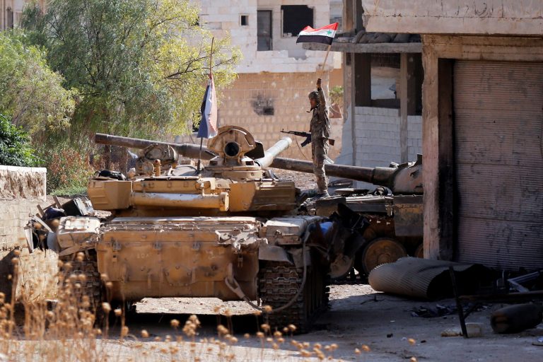 A Syrian army soldier holds a Syrian flag as he stands on a military vehicle in Khan Sheikhoun, Idlib, Syria August 24, 2019. REUTERS/Omar Sanadiki - RC1B10956C80