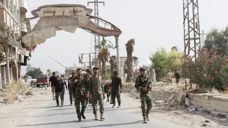 Syrian soldiers walk at the entrance of Daraya, a besieged Damascus suburb, on Friday