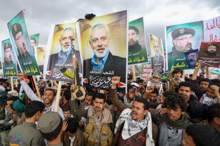 TOPSHOT - Yemenis wave flags and lift placards of Hezbollah senior commander Fuad Shukr, who was killed in an Israeli strike, and slain Hamas chief Ismail Haniyeh, during a rally in the Huthi-controlled capital Sanaa on August 2, 2024, denouncing their killing, amid the ongoing conflict in the Gaza Strip between Israel and the Palestinian Hamas movement. Haniyeh, the Palestinian armed group's political chief, who was killed on July 31 in the Iranian capital Tehran, played a key role in mediated talks aimed at ending nearly 10 months of war between Hamas and Israel in Gaza. (Photo by Abdallah ADEL / AFP)