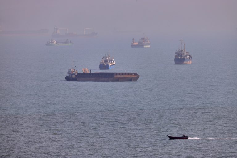A small boat sails past cargo ships and other commercial vessels anchored in the Strait of Hormuz off Bandar Abbas, Iran, Wednesday, Aug. 5, 2026. (Amirhosein Khorgooi/ISNA via AP)